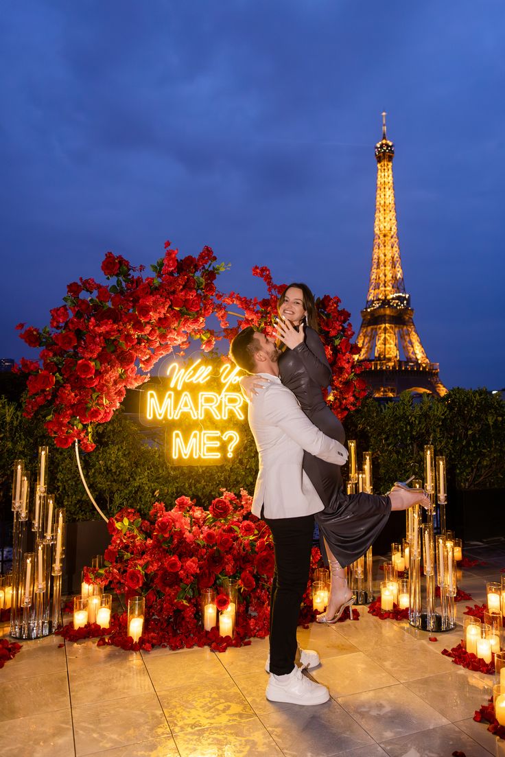 a man and woman are dancing in front of the eiffel tower at night