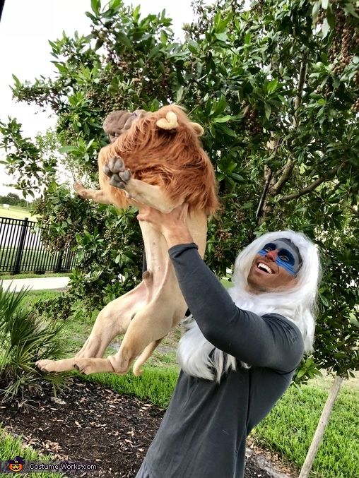 a man is holding up a dog in the air while wearing sunglasses and a wig