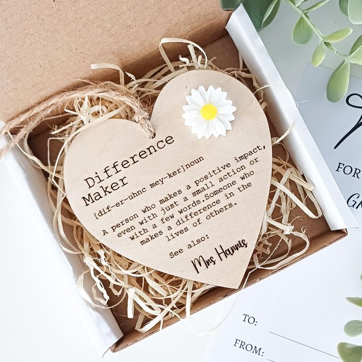 a box with a heart shaped paper on top of it next to some cards and flowers