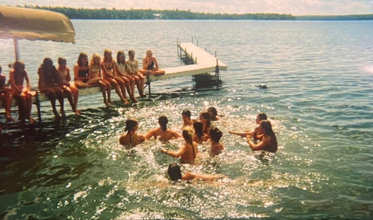 some people are swimming in the water near a dock