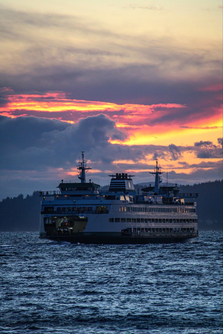 a large boat floating on top of a body of water under a cloudy sky at sunset