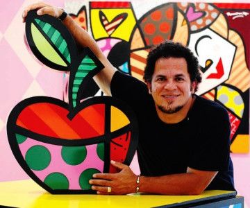 a man leaning against a colorful wall with an apple cutout in the shape of a heart