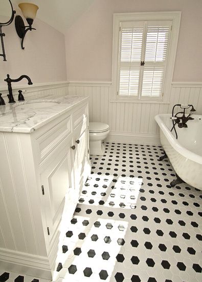 a white bathroom with black and white floor tiles