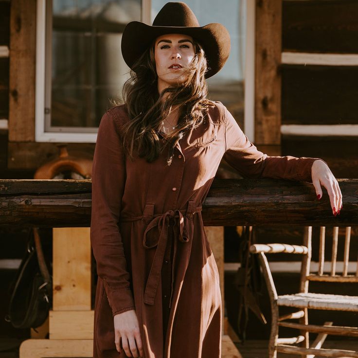 With a rich tobacco color and authentic Western-inspired design, this long-sleeve, mid-length dress features one-point front and back yokes, a full-front snap placket, and curved snap cuffs. It has a self-tie belt with belt loops, two smile pockets and two two side seam pockets. Made from sustainable Tencel twill, it pairs equally well with a cowboy hat and boots as it does with a sun hat and sandals. Single Point Front And Back Yokes Smile Pockets Curved Snap Cuffs Side Seam Pockets Full Front Western Business Casual, Cute Cowgirl Outfits, Modern Farmer, Two Two, Western Dress, Wide Trousers, Cowgirl Outfits, Mid Length Dresses, Western Dresses