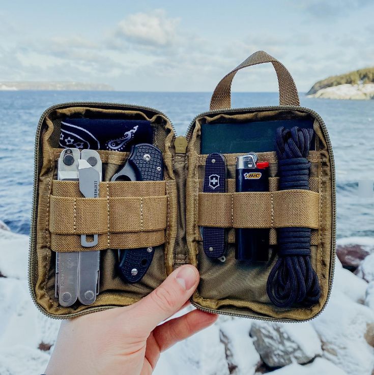 a person holding an open case filled with various items in front of snow covered ground