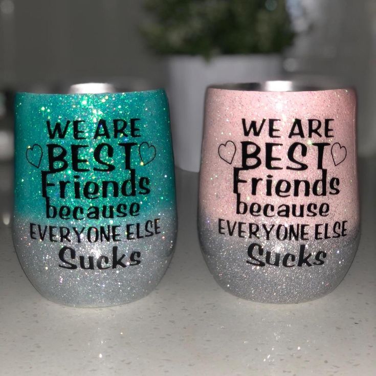 two glitter wine glasses sitting on top of a counter next to each other with words written on them