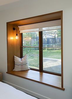 a window seat with pillows on it in front of a sliding glass door that leads to a yard