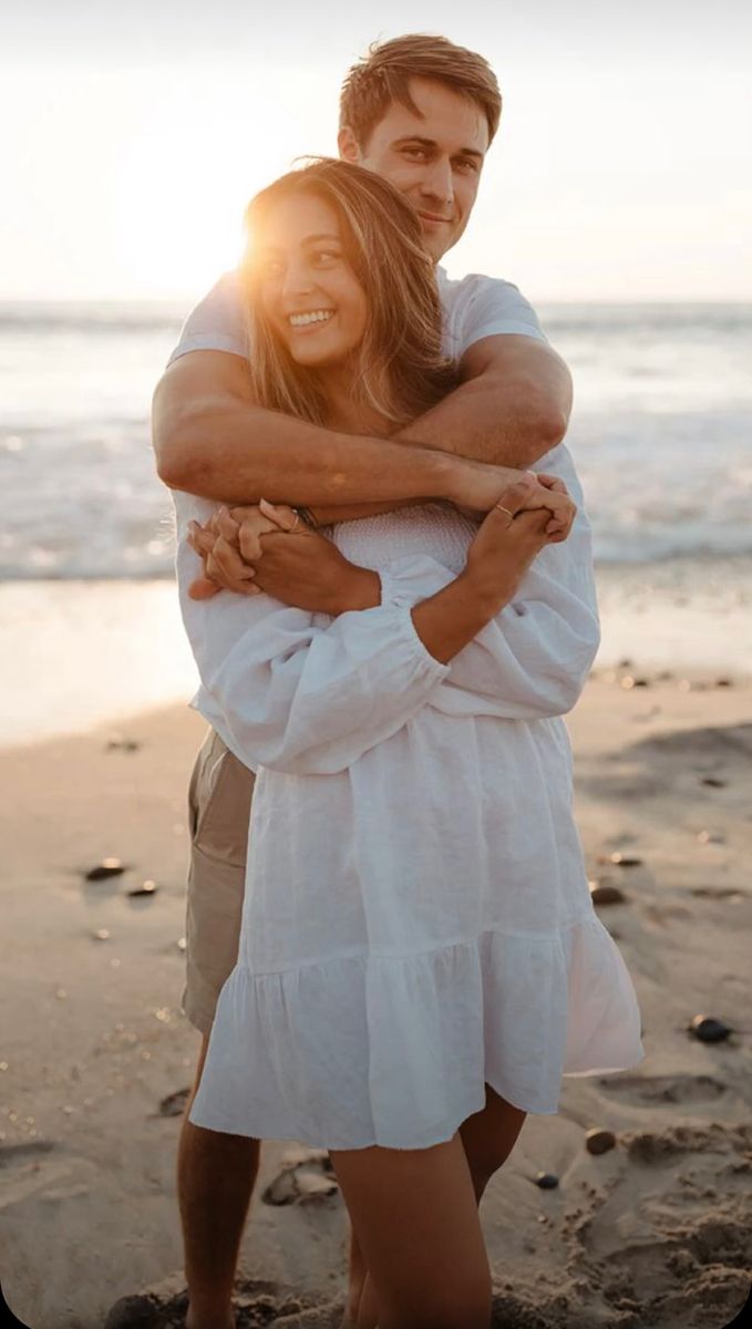 a man and woman hugging on the beach