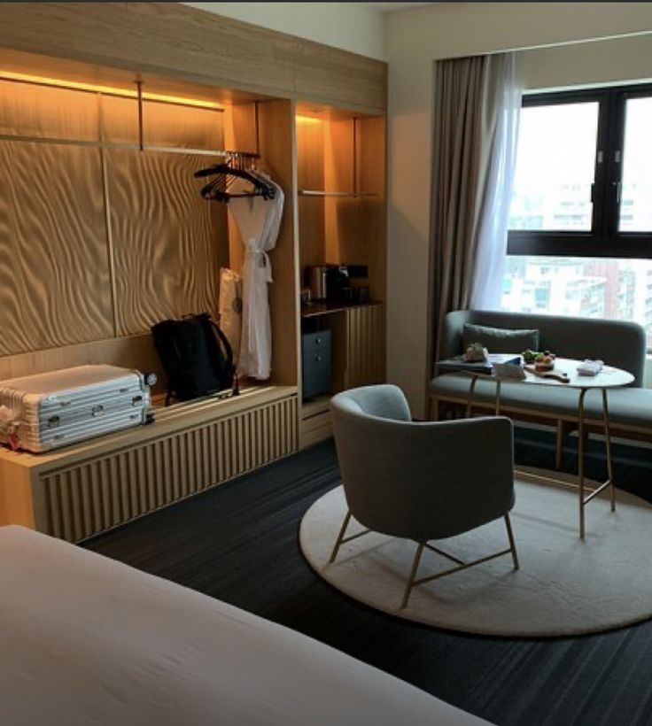 a hotel room with a bed, desk and chair in it next to a large window