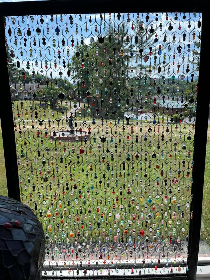 a window covered in lots of different colored glass bottle caps next to a black tire