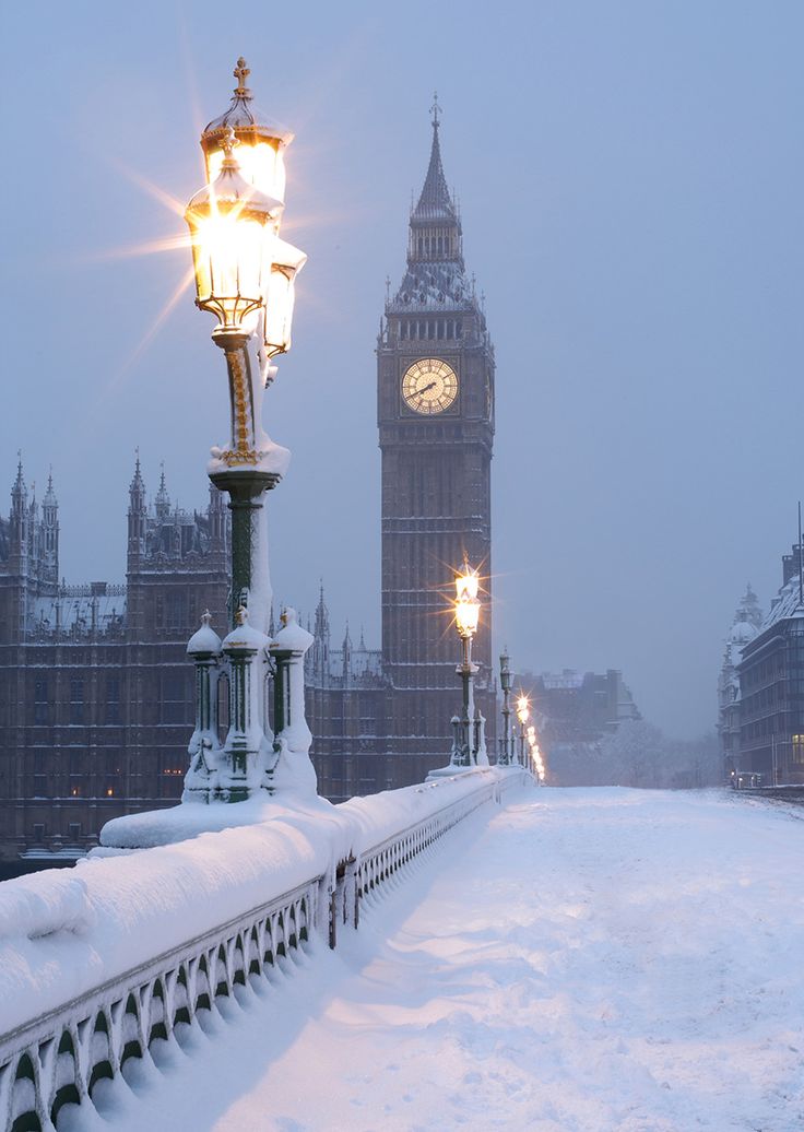 the big ben clock tower towering over the city of london covered in snow at night