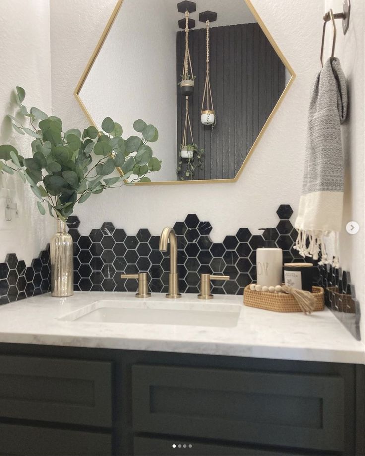 a bathroom with black and white hexagonal tiles on the wall, gold faucet