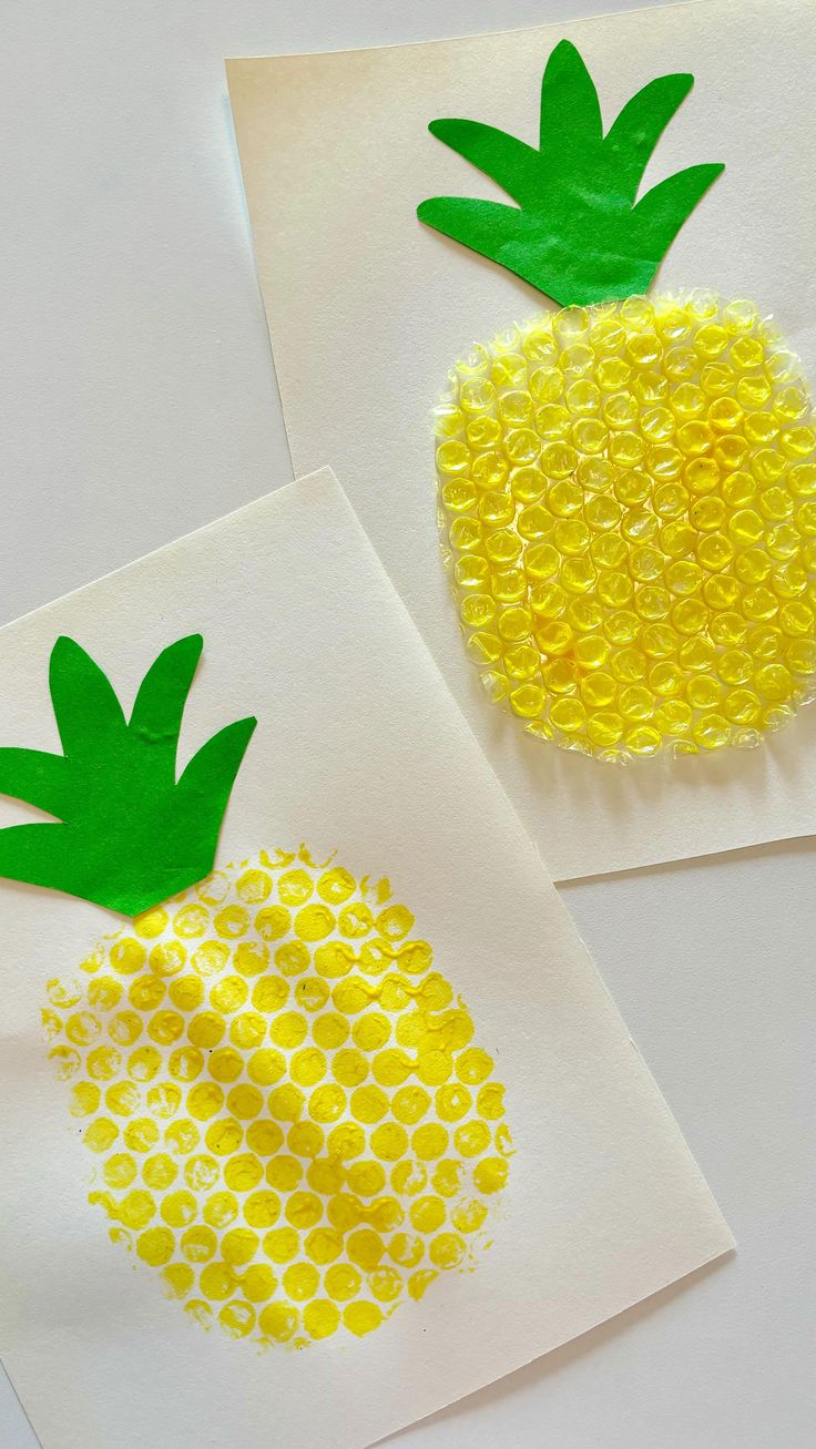 two pineapples made out of buttons on white paper with yellow circles and green leaves