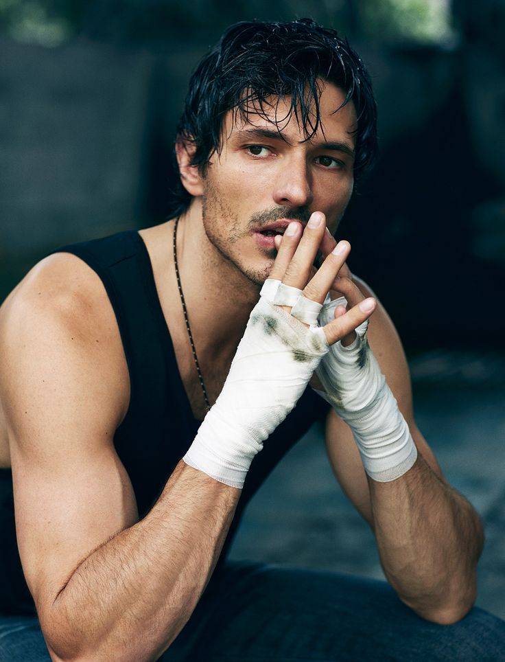 a man sitting on the ground with his hands clasped to his chest and wearing white gloves