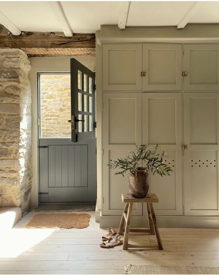 a plant is sitting on a stool in the middle of a room with stone walls