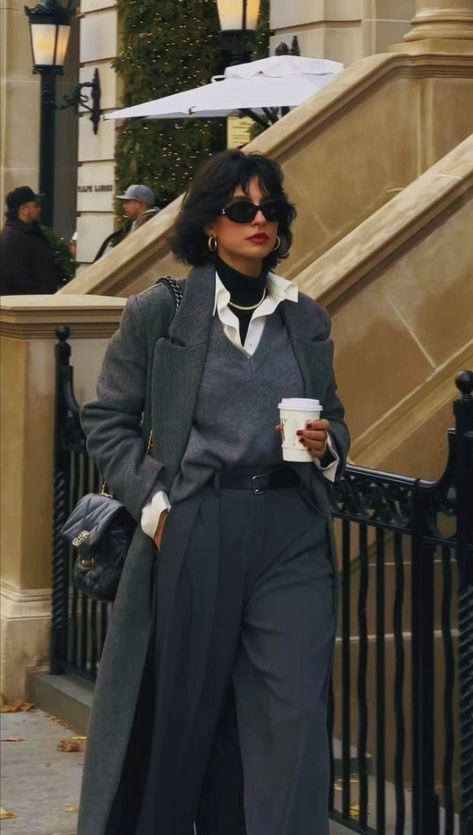 a woman walking down the street with an umbrella over her head and holding a coffee cup