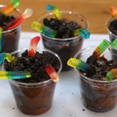 four plastic cups filled with dirt and toothbrushes on top of a white tray