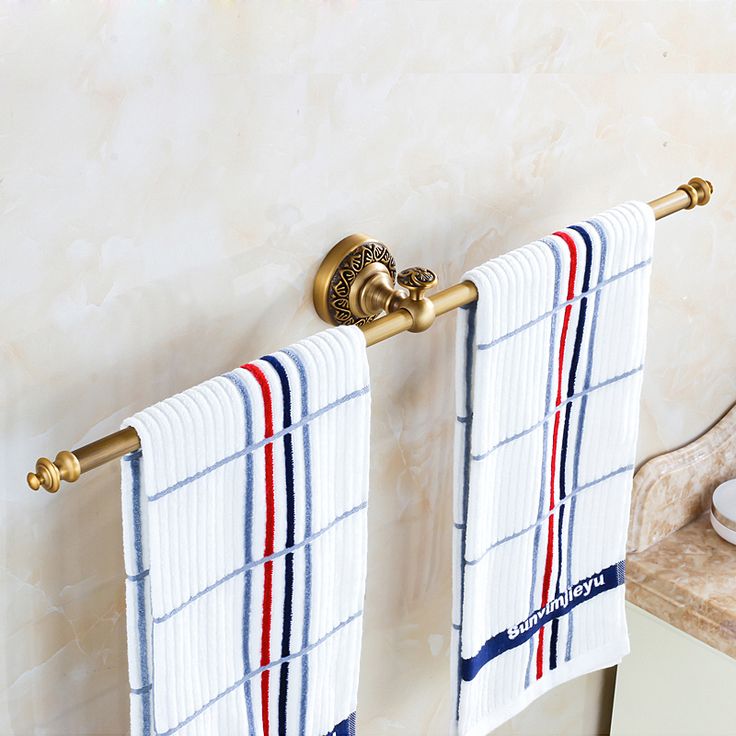 two towels are hanging on the wall next to a towel rack with three gold handles