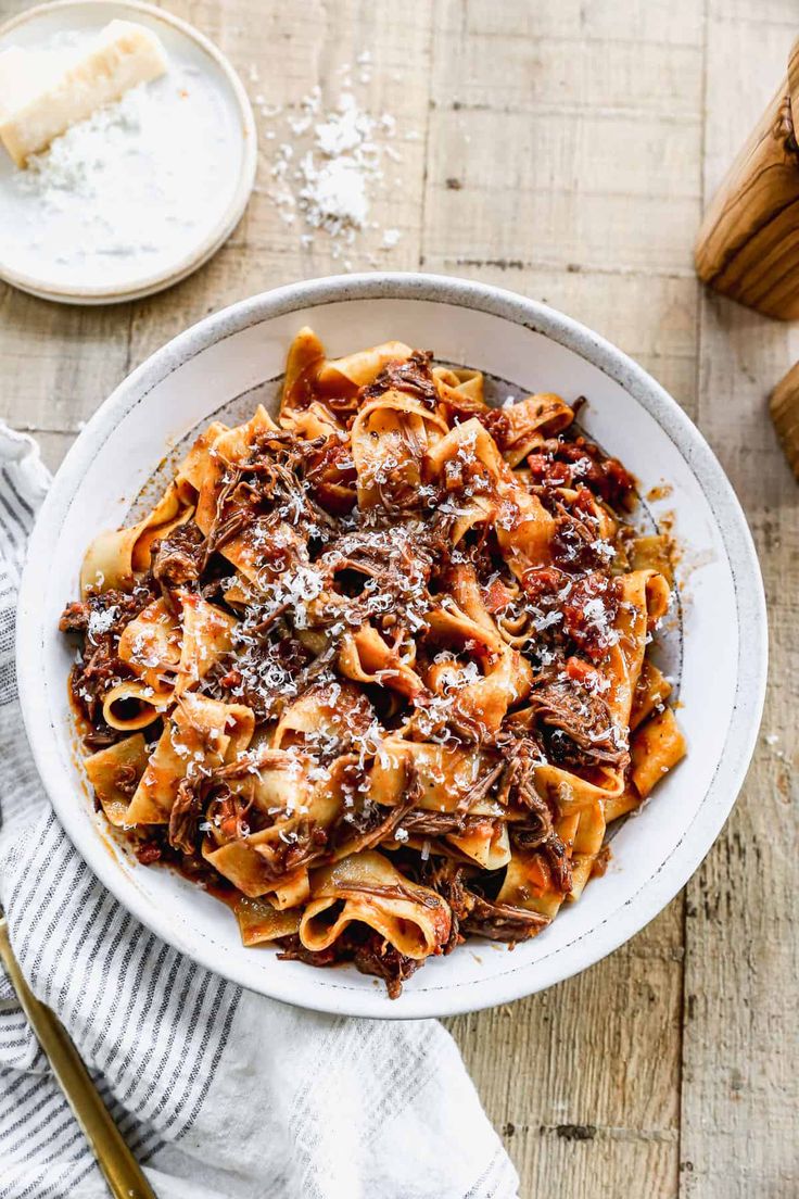 a white bowl filled with pasta covered in sauce and parmesan cheese on top