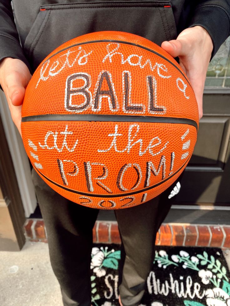 a person holding a basketball with words written on it in front of a door way