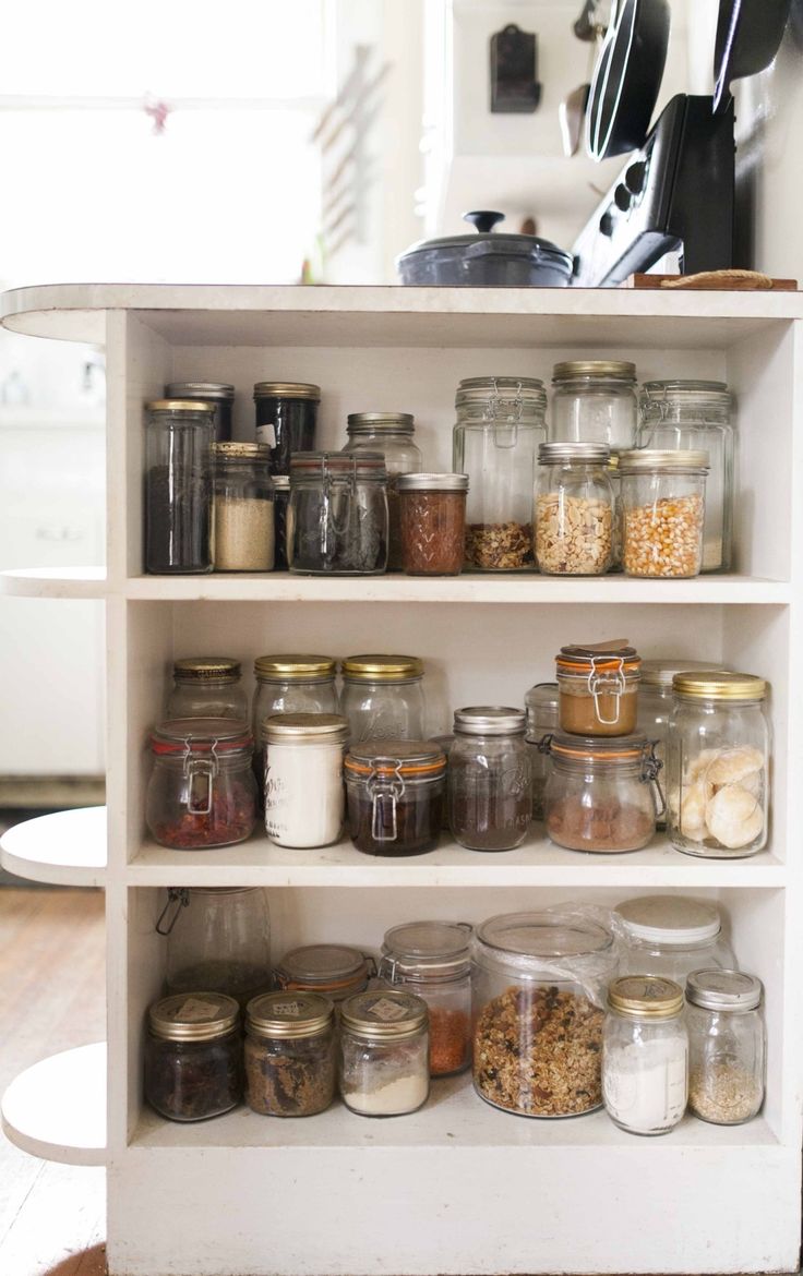 an open cabinet filled with lots of different types of jars and containers on top of it