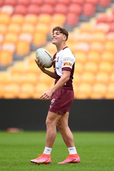 a young man holding a soccer ball on top of a field in front of an empty stadium