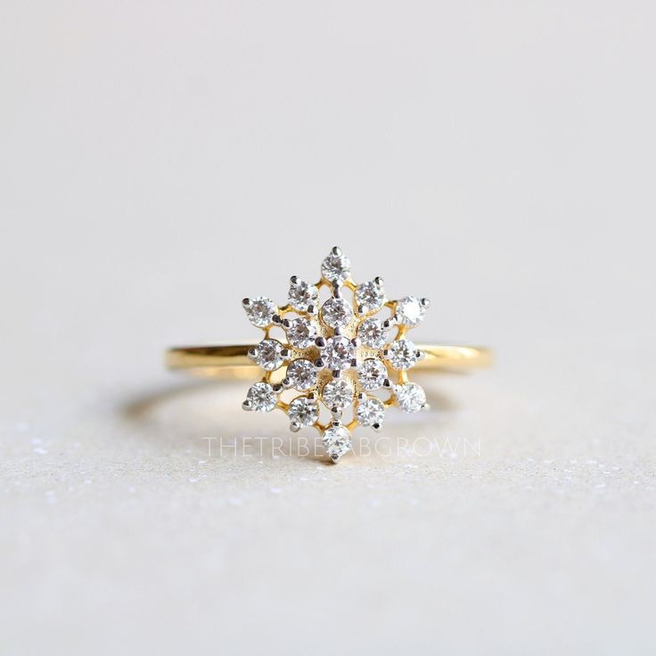 a yellow gold ring with two white diamonds on the front and center, sitting on a light gray surface