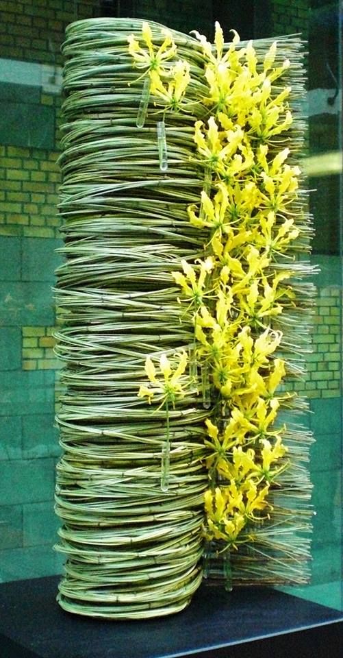 a tall vase with yellow flowers sitting on top of a table