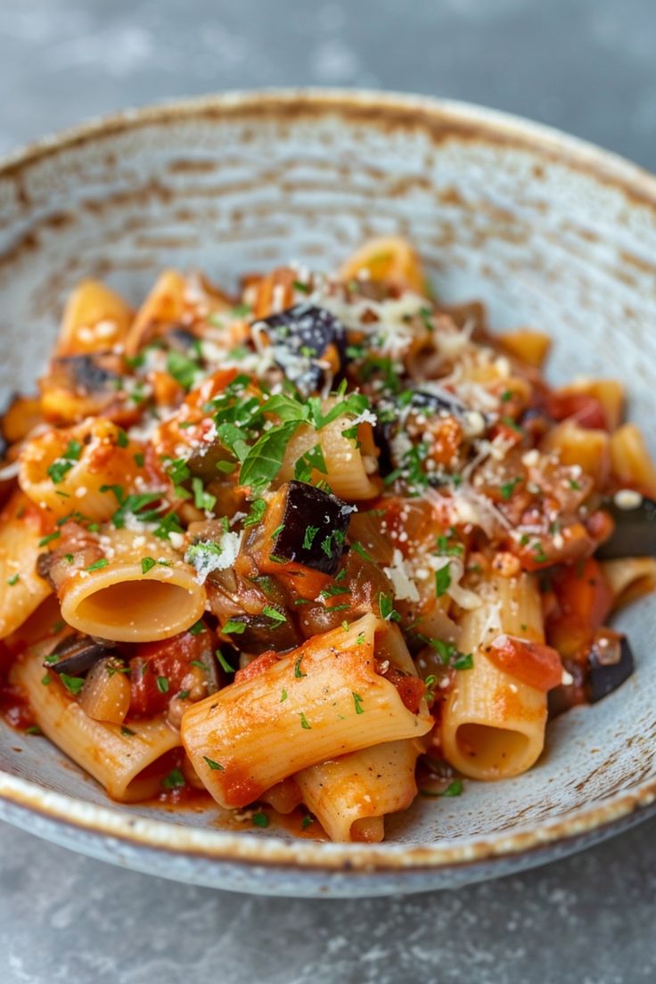 a bowl filled with pasta covered in sauce and parmesan cheese