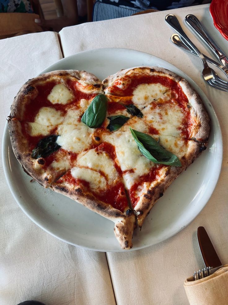 a heart shaped pizza sitting on top of a white plate