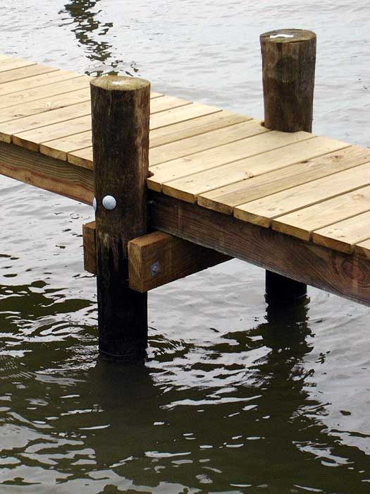 a wooden dock with two poles sticking out of the water