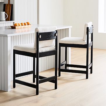 two black and white chairs sitting next to each other on a wooden floor in front of a counter