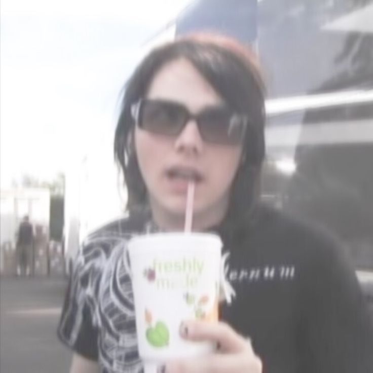 a woman in sunglasses is drinking from a cup with a straw and looking at the camera