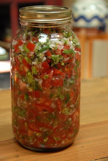 a glass jar filled with lots of different types of food on top of a wooden table