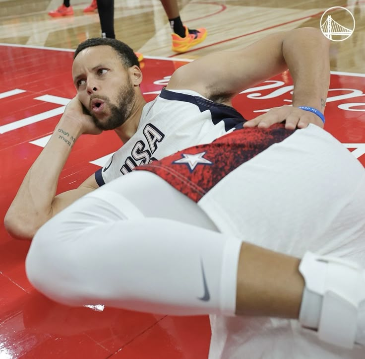 a basketball player laying on the floor with his head in his hands