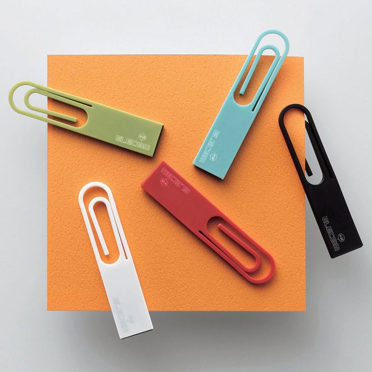 three different colored paper clips on an orange surface