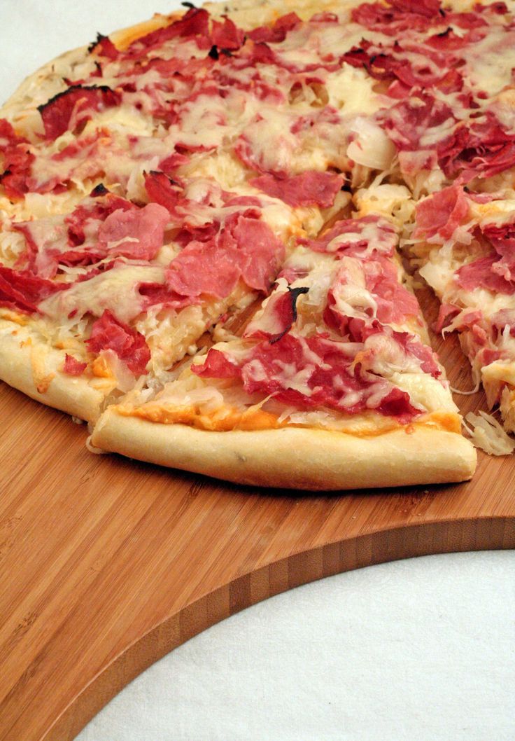 a pizza sitting on top of a wooden cutting board next to a slice missing from it