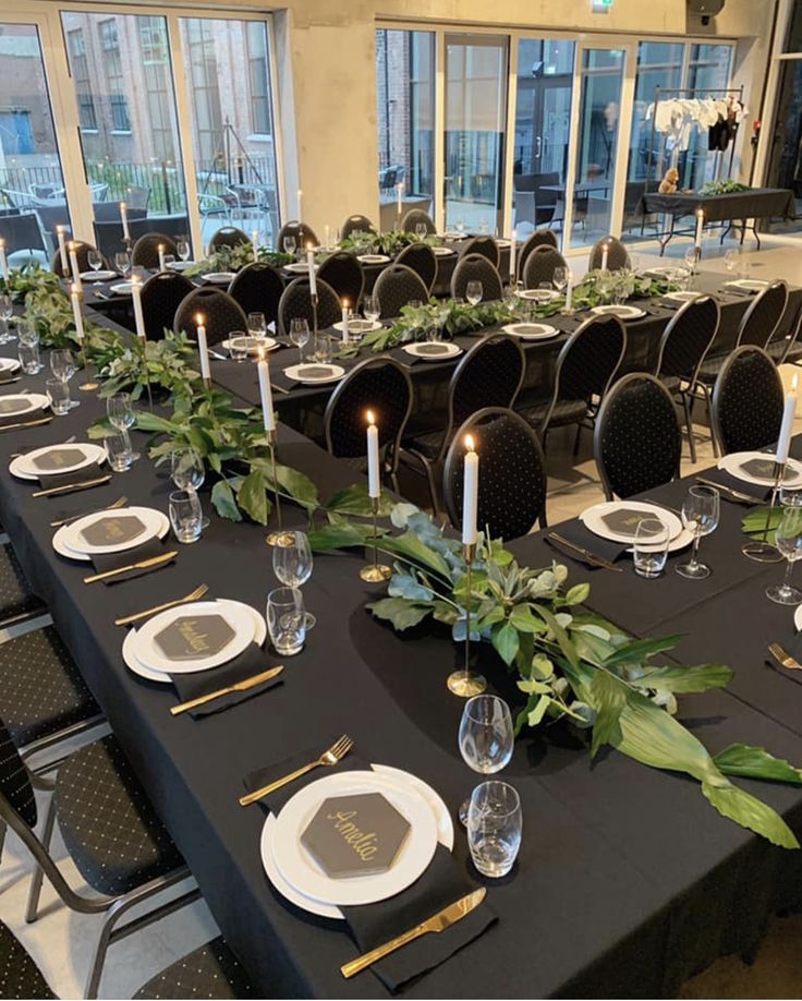 a long table set with place settings and candles