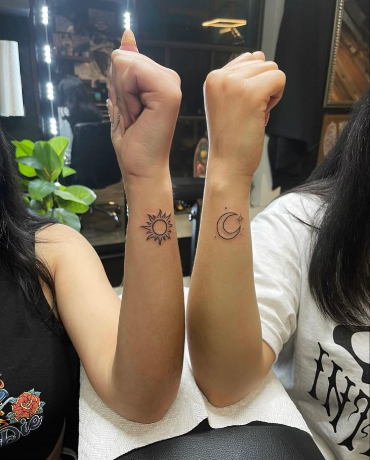 two girls with matching tattoos on their arms, one has the sun and the other has the moon