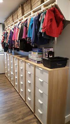 an organized closet with clothes hanging on the wall and drawers in front of it,