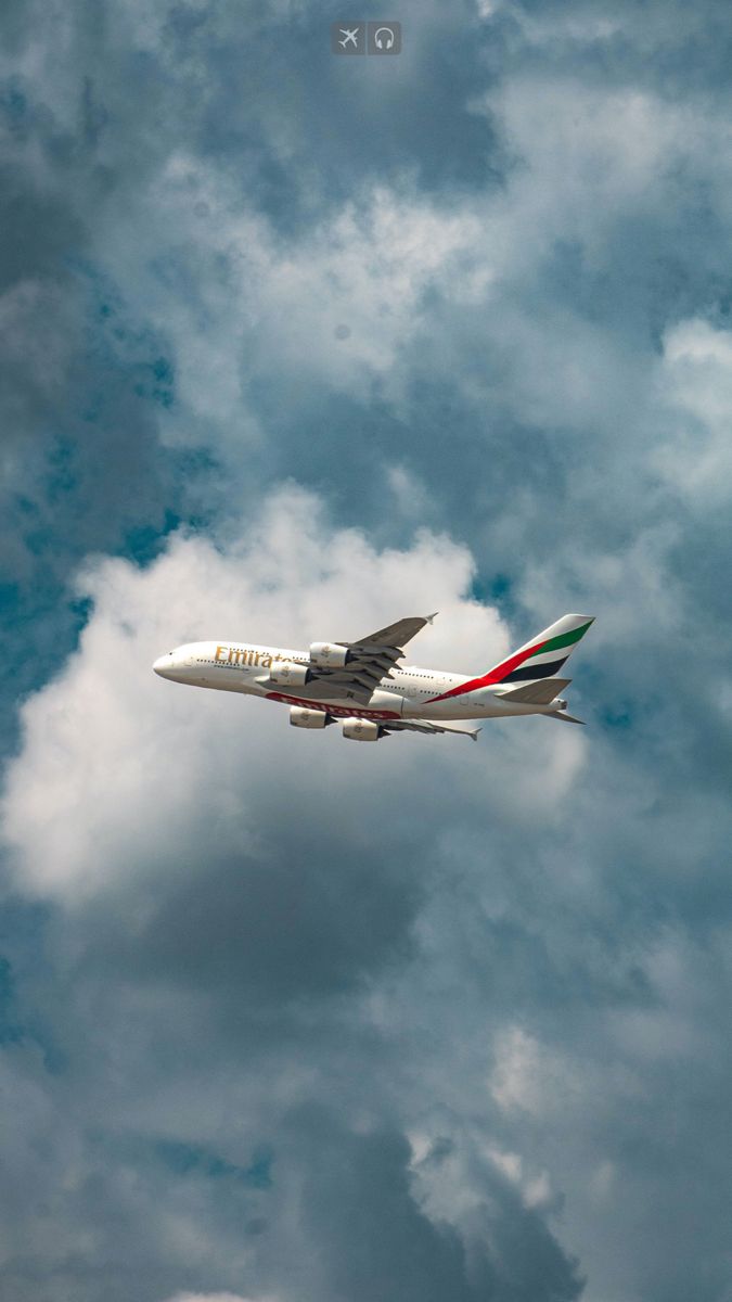 an airplane is flying in the sky with clouds behind it on a partly cloudy day