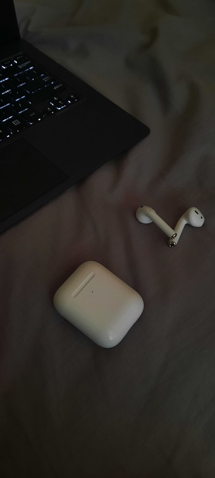 an apple airpods sitting on top of a bed next to a laptop