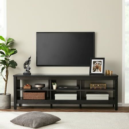 a flat screen tv sitting on top of a wooden entertainment center next to a potted plant