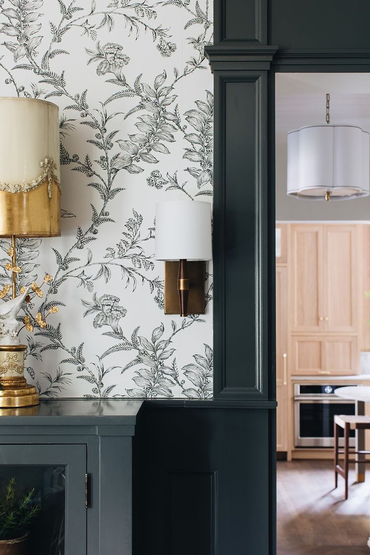 a lamp on top of a cabinet next to a wallpapered room with a table and chairs