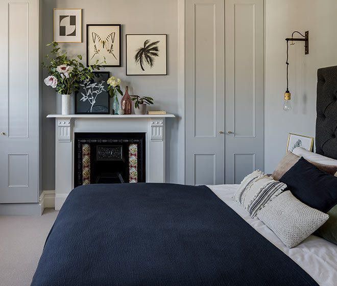 a bedroom with a fireplace, bed and pictures on the wall above it's headboard