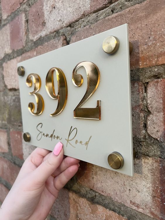 a person holding up a plaque with the number two in gold on it that reads,'922 south road '