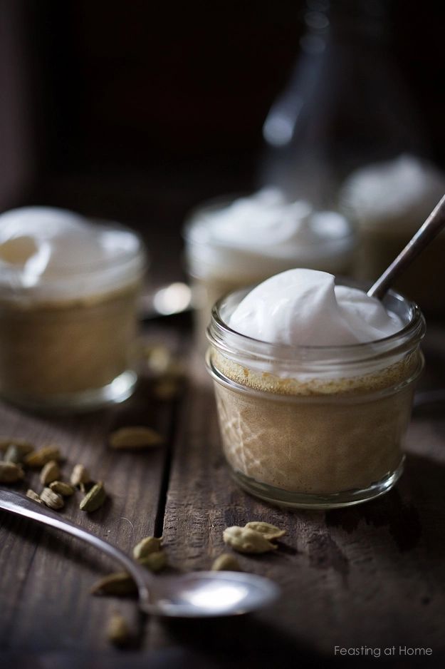 two jars filled with whipped cream on top of a wooden table next to spoons