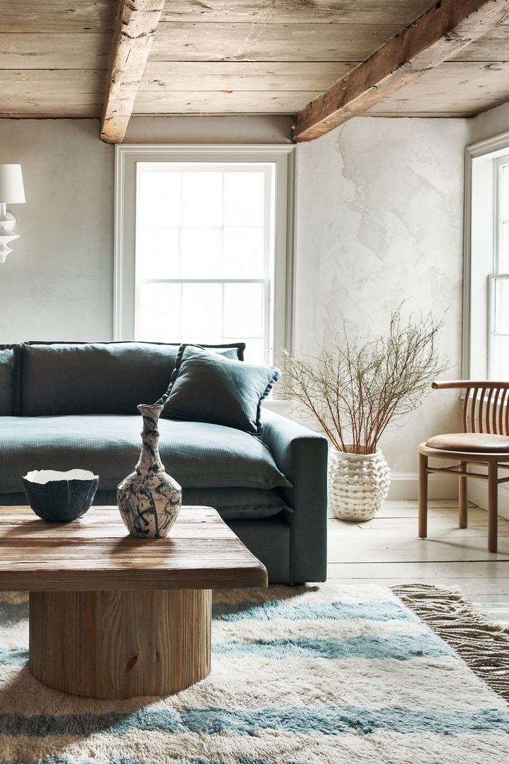 a living room with a blue couch and coffee table in front of two large windows