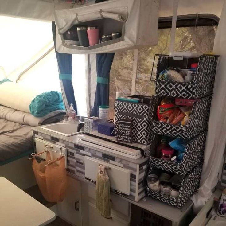 the inside of a camper with various items and storage bins on top of it