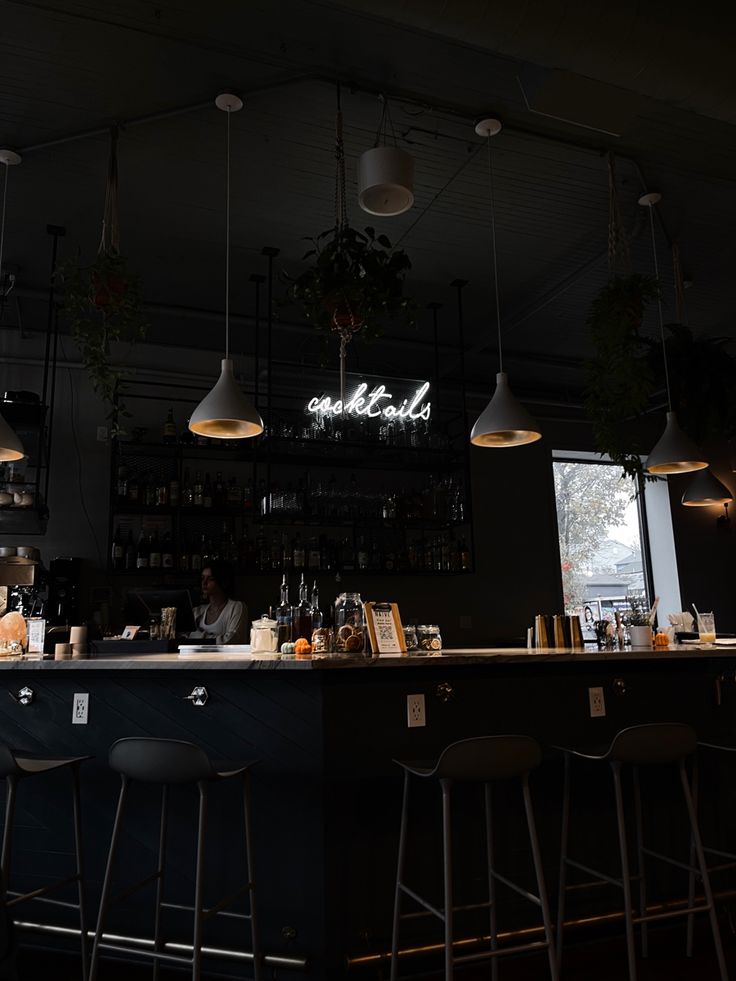 a bar with several stools in front of it and lights hanging from the ceiling